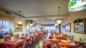 A spacious dining area with multiple tables and chairs, adorned with red tablecloths and patterned upholstery. - Hotel Fabrizio (Caorle)