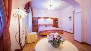 A bedroom with a bed, a bedside table, a chair, a lamp, and a vase with flowers. - Hotel Fabrizio (Caorle)