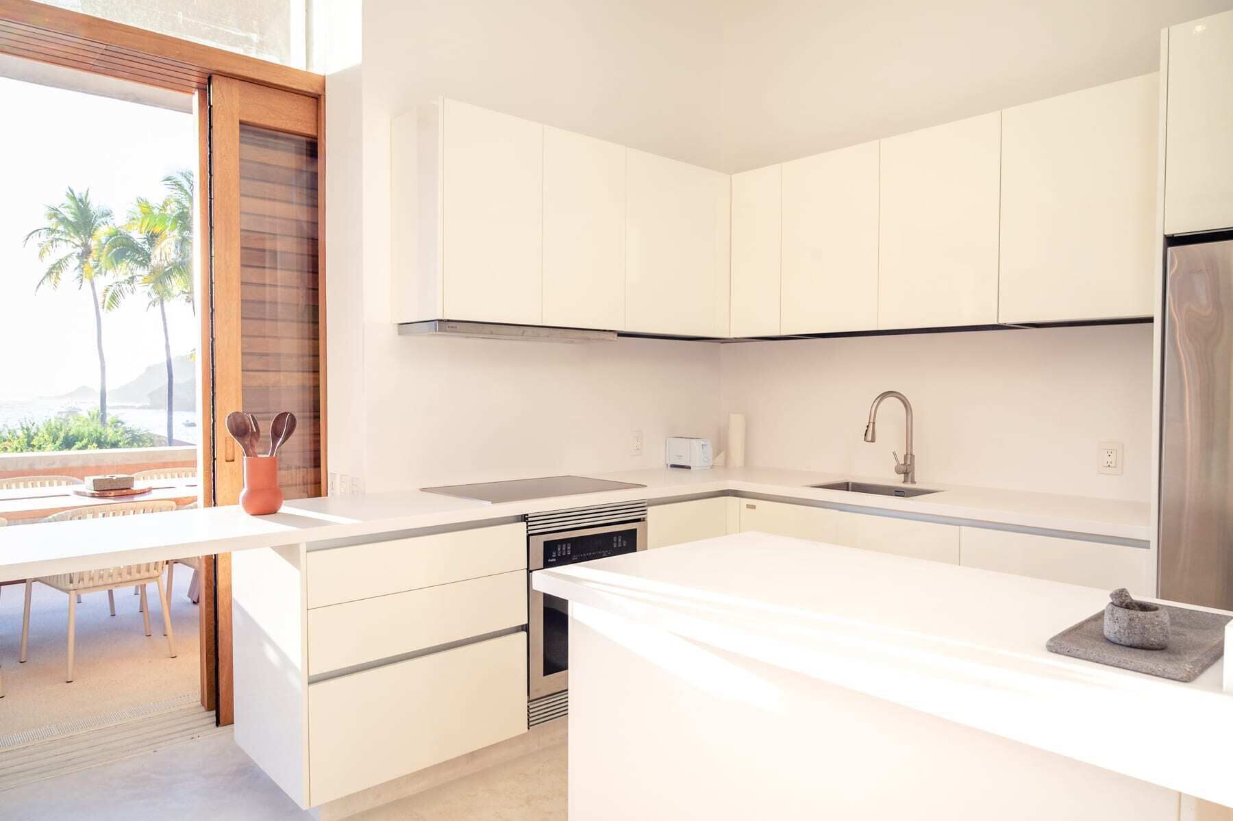 Een moderne keuken met witte kasten, een roestvrijstalen spoelbak en een inbouwoven.