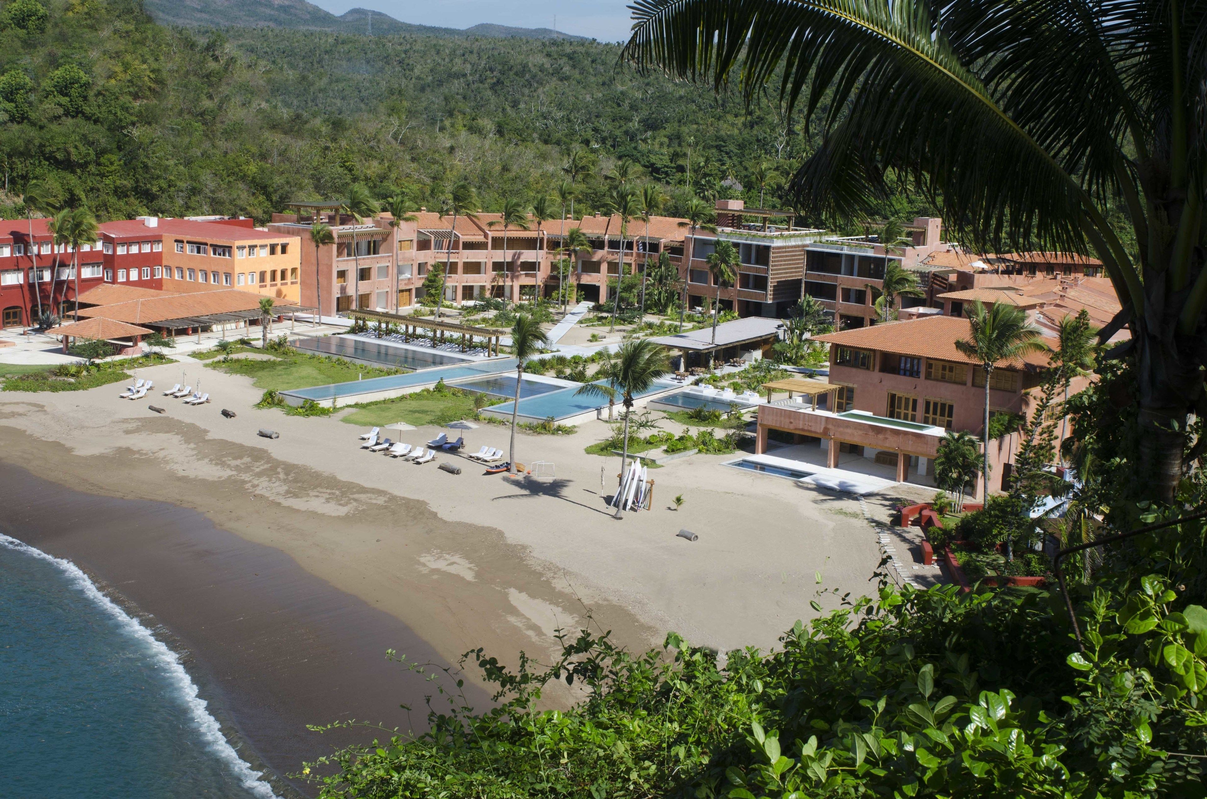 A resort with multiple buildings, a beach, and a pool area.