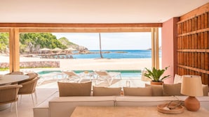 A beachside room with a view of the ocean, a pool, and outdoor seating.