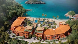 A resort with multiple buildings, a swimming pool, and a beach with palm trees.