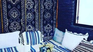 Una habitación de estilo marroquí tradicional, con cojines a rayas y una mesa baja dispuesta para una comida.