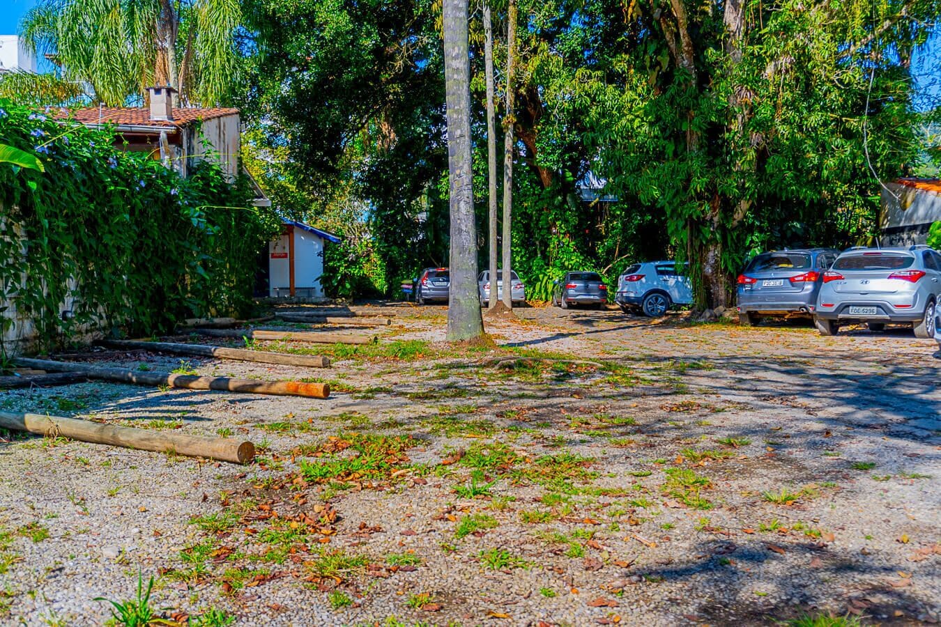 Un espace de stationnement avec des voitures, des arbres et un bâtiment doté d’un toit rouge.