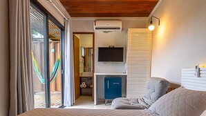 Ein Schlafzimmer mit einem Bett, einem Schreibtisch mit Fernseher, einem blauen Schrank und einer Hängematte.