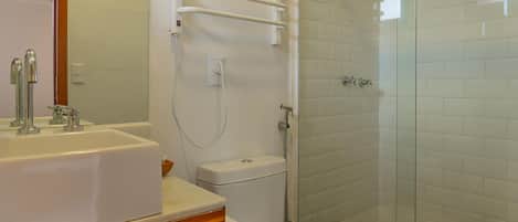 A bathroom with a white sink, toilet, and shower.