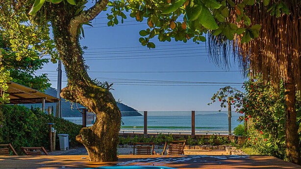 Eine Holzterrasse mit Schwimmbad, einem Baum und Blick aufs Meer.