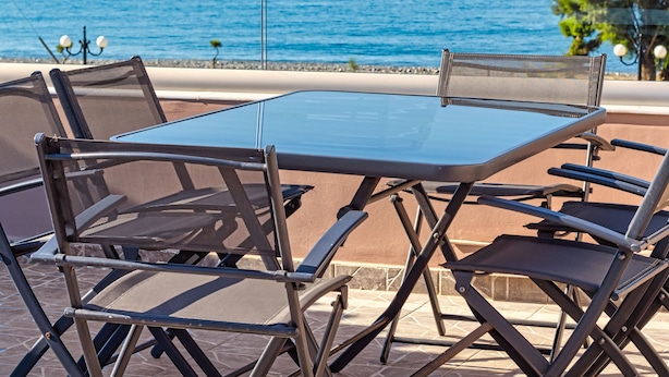 A table and chairs set up on a patio overlooking a body of water. - Oliva Beach Studios & Apartments (Platanias)