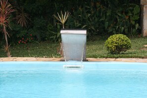 Una piscina al aire libre, sillones reclinables de piscina