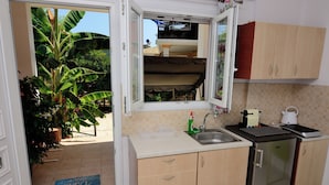 Eine kompakte Küchenzeile mit Spüle, kleinem Kühlschrank und einem Fenster mit Blick ins Freie.