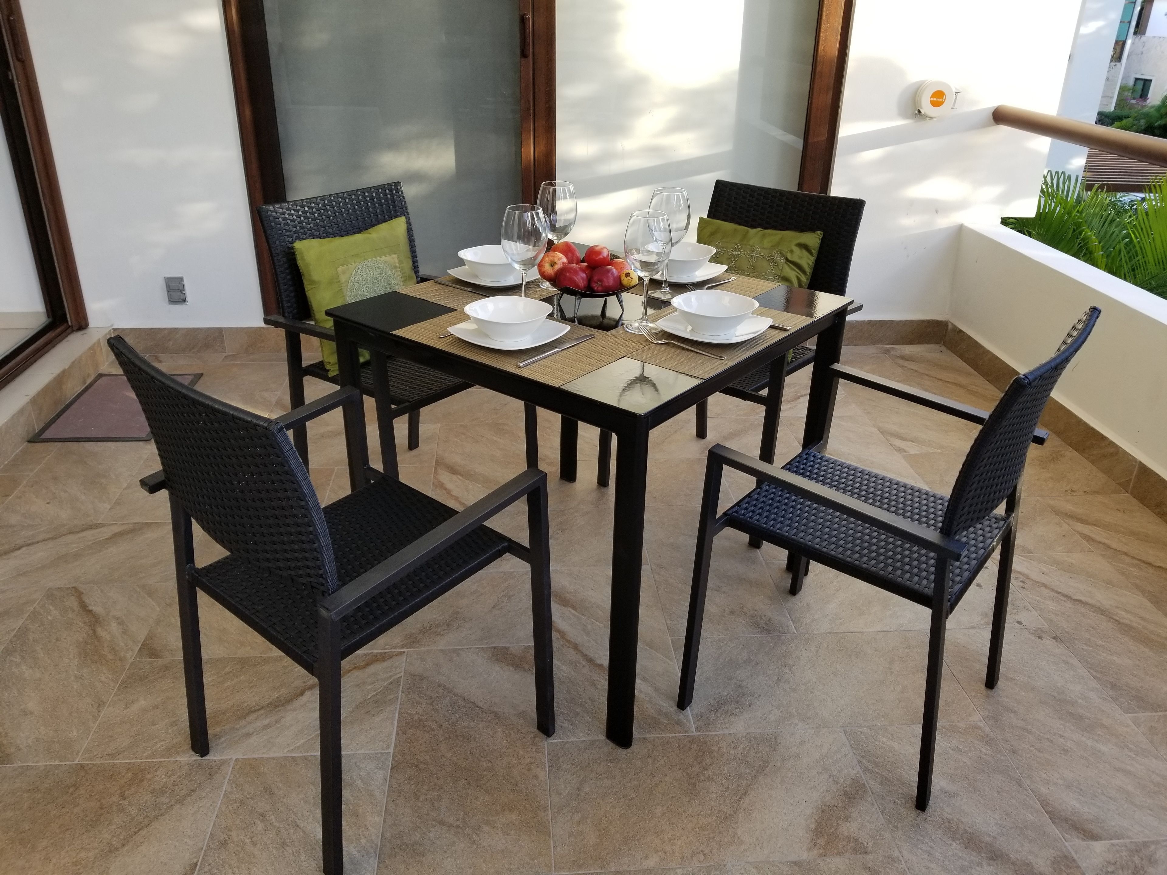 Un coin repas avec une table dressée pour quatre personnes, entourée de chaises.