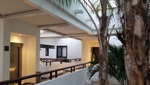 A modern interior with a staircase, white walls, and a palm tree. - Charming 2 bedroom Apartment within Bahia Principe Resort (Akumal)