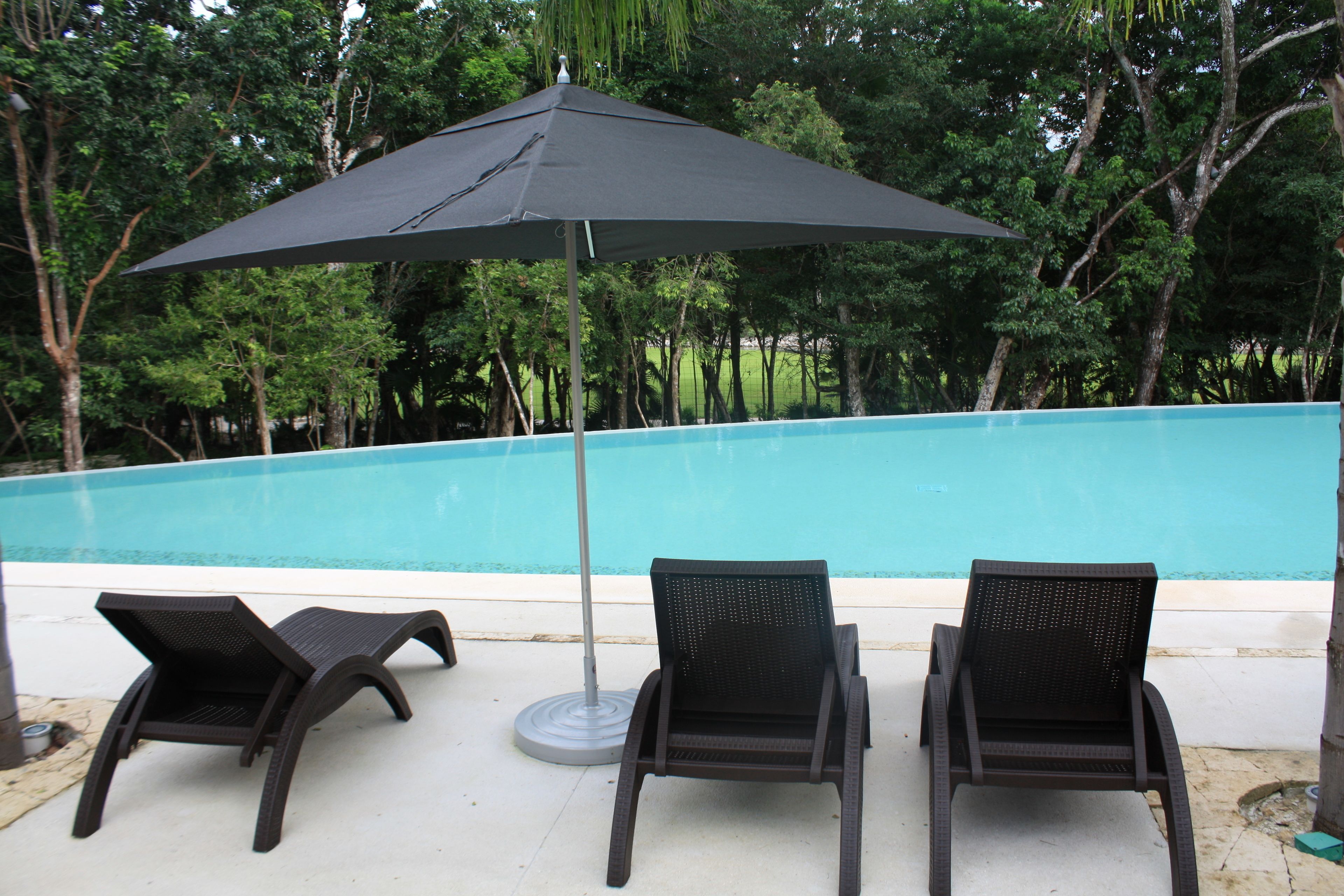 A poolside area with two lounge chairs and a large umbrella.