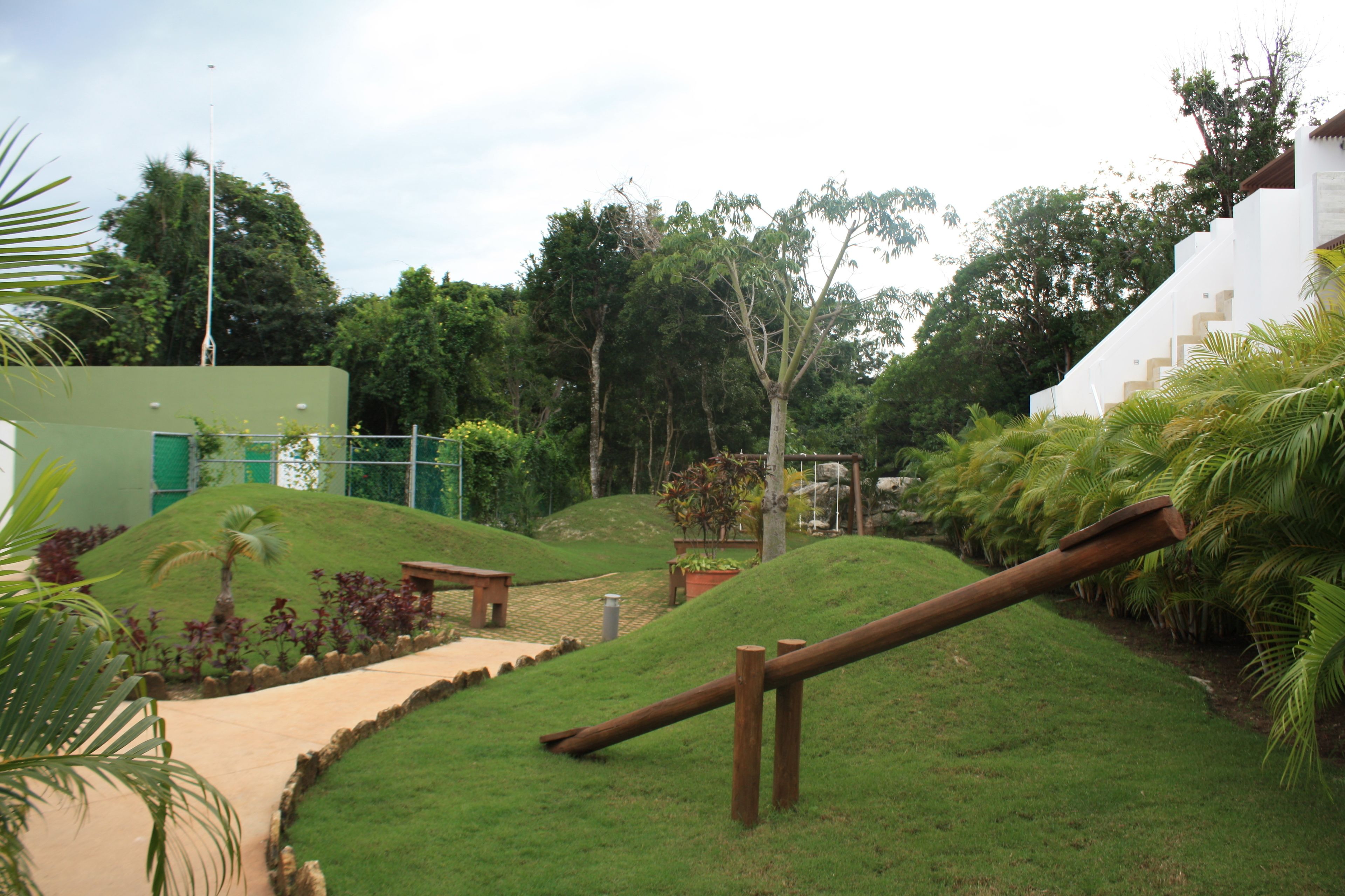 A landscaped garden with a pathway, wooden fence, and a building with a green door.