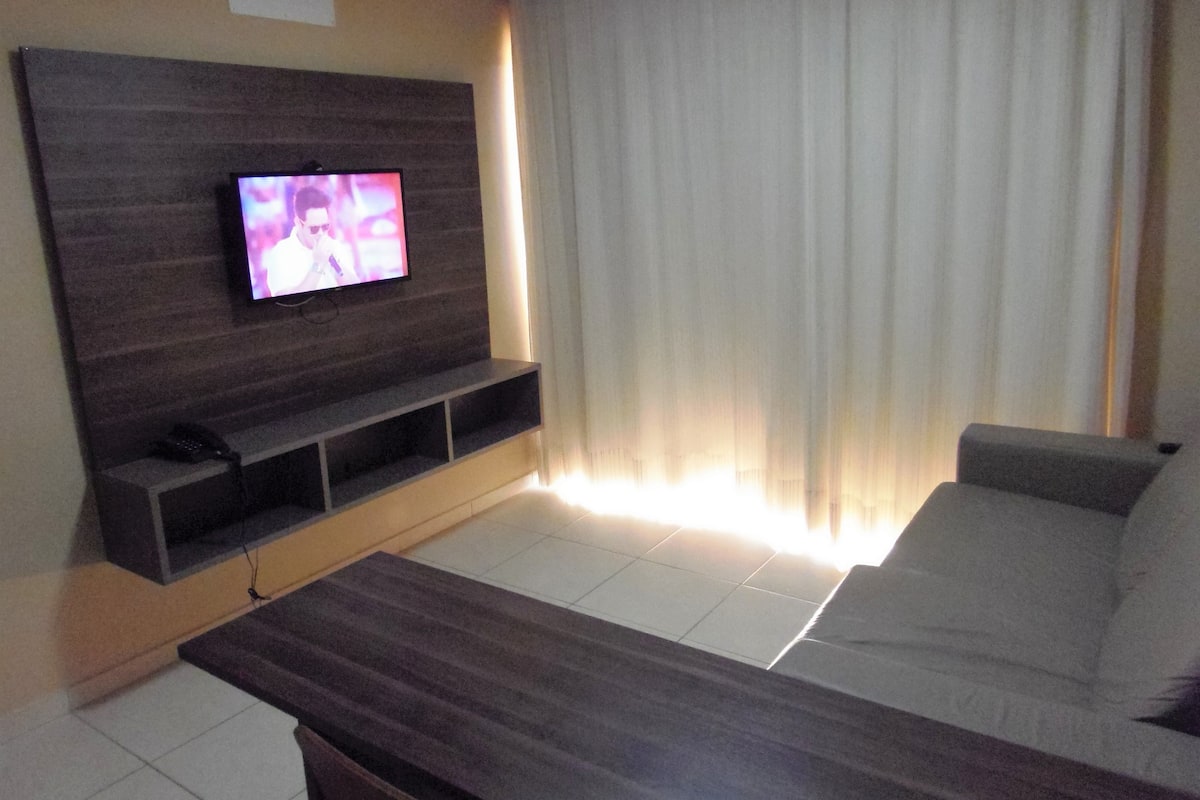 A modern living room with a flat-screen TV mounted on a wooden wall, a sofa, and a coffee table.