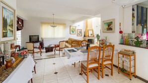 Uma sala de estar ampla com área de jantar, televisão e lareira.