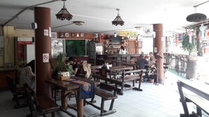 Ein Restaurant mit Holztischen und -bänken, einer Bar und Blick auf die Straße.
