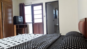 Ein Zimmer mit einem Bett, einem Fernseher auf einer Holzkommode und einer Tür zu einem anderen Raum.