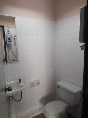 A small, basic bathroom with a toilet, sink, and shower. - Inter Inn Chiangmai (Chiang Mai)