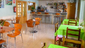 Un restaurante con zona de bar, varias mesas y sillas, y una variedad de botellas en estanterías.