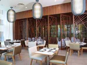 Un comedor moderno con separadores de madera, mesas redondas y sillas.