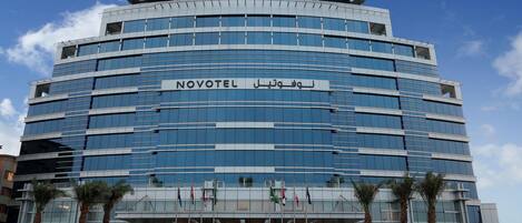 A modern hotel with a curved facade, multiple floors, and a prominent entrance.