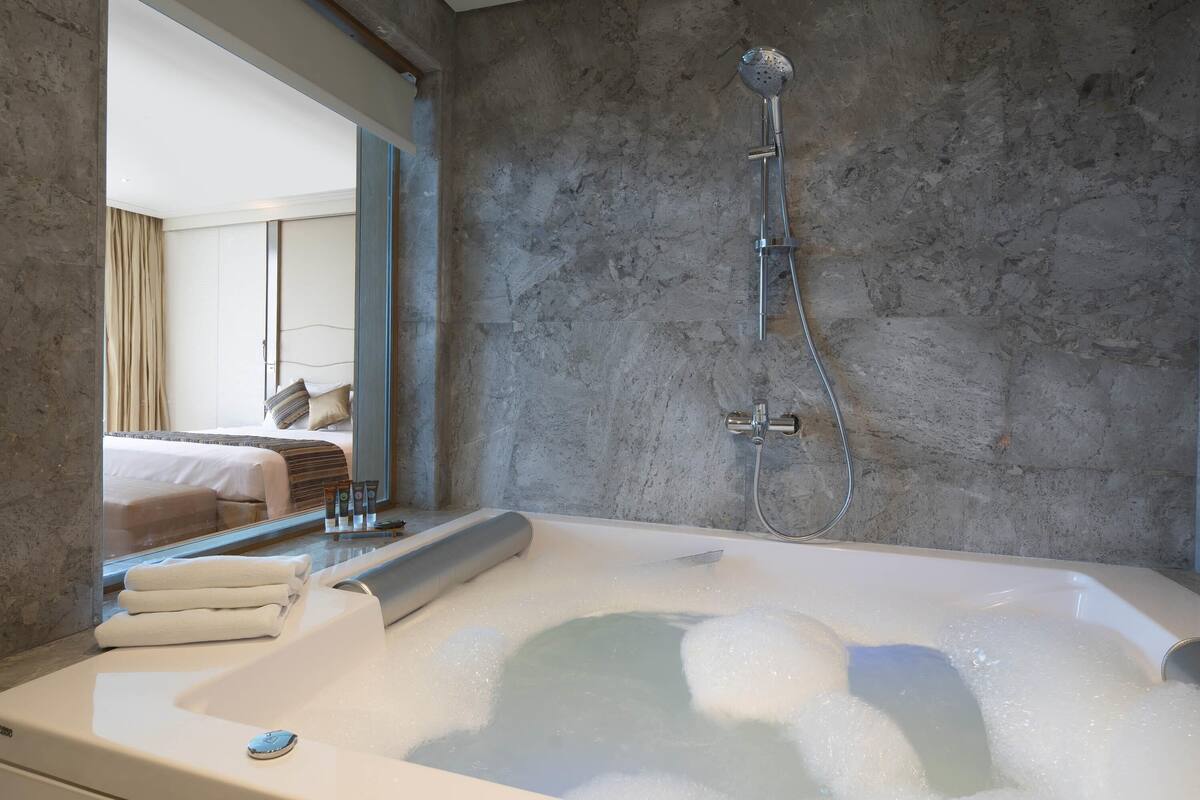 Un baño moderno con una bañera grande, ducha y un espejo que refleja la habitación.