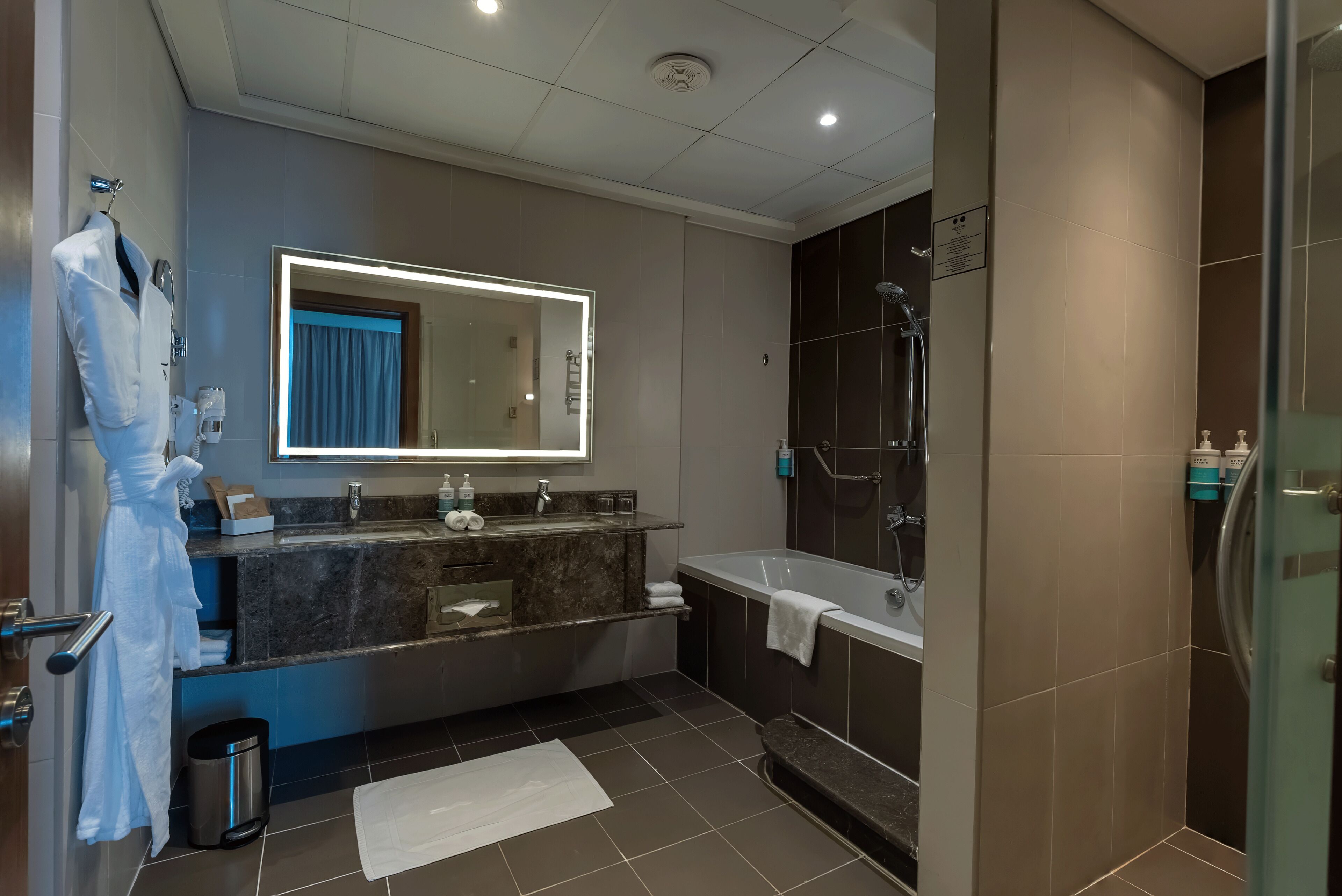 A modern bathroom with a large mirror, a bathtub, a shower, and a vanity with a sink.