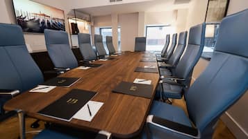 A conference room with a long table, blue chairs, and a large window.