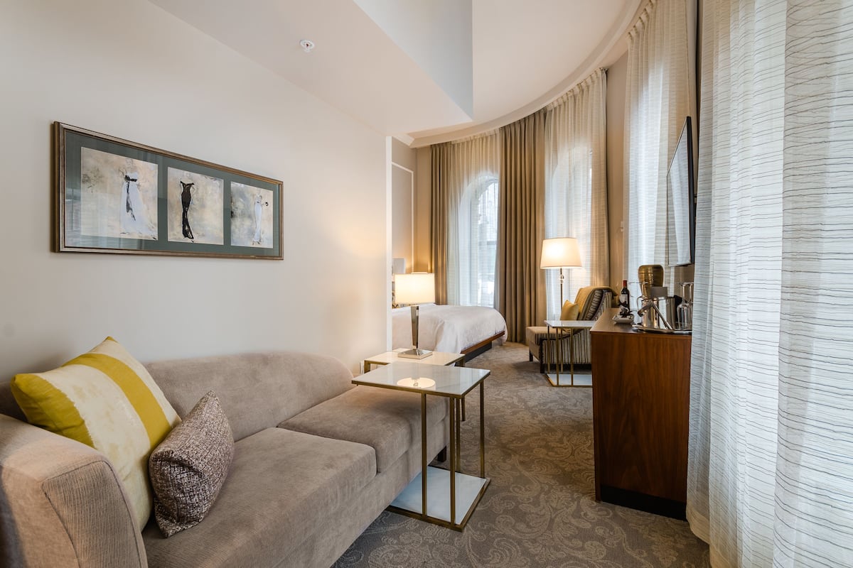 Ein Hotelzimmer mit einer Sitzecke, einem Schreibtisch, einem Bett und einem Essbereich.