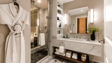 A modern bathroom with a glass-enclosed shower, a marble sink, and a large mirror.