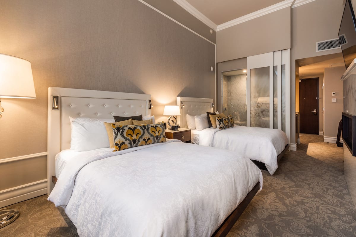 Ein Hotelzimmer mit zwei Betten, einem großen Spiegel und einem Fernseher.