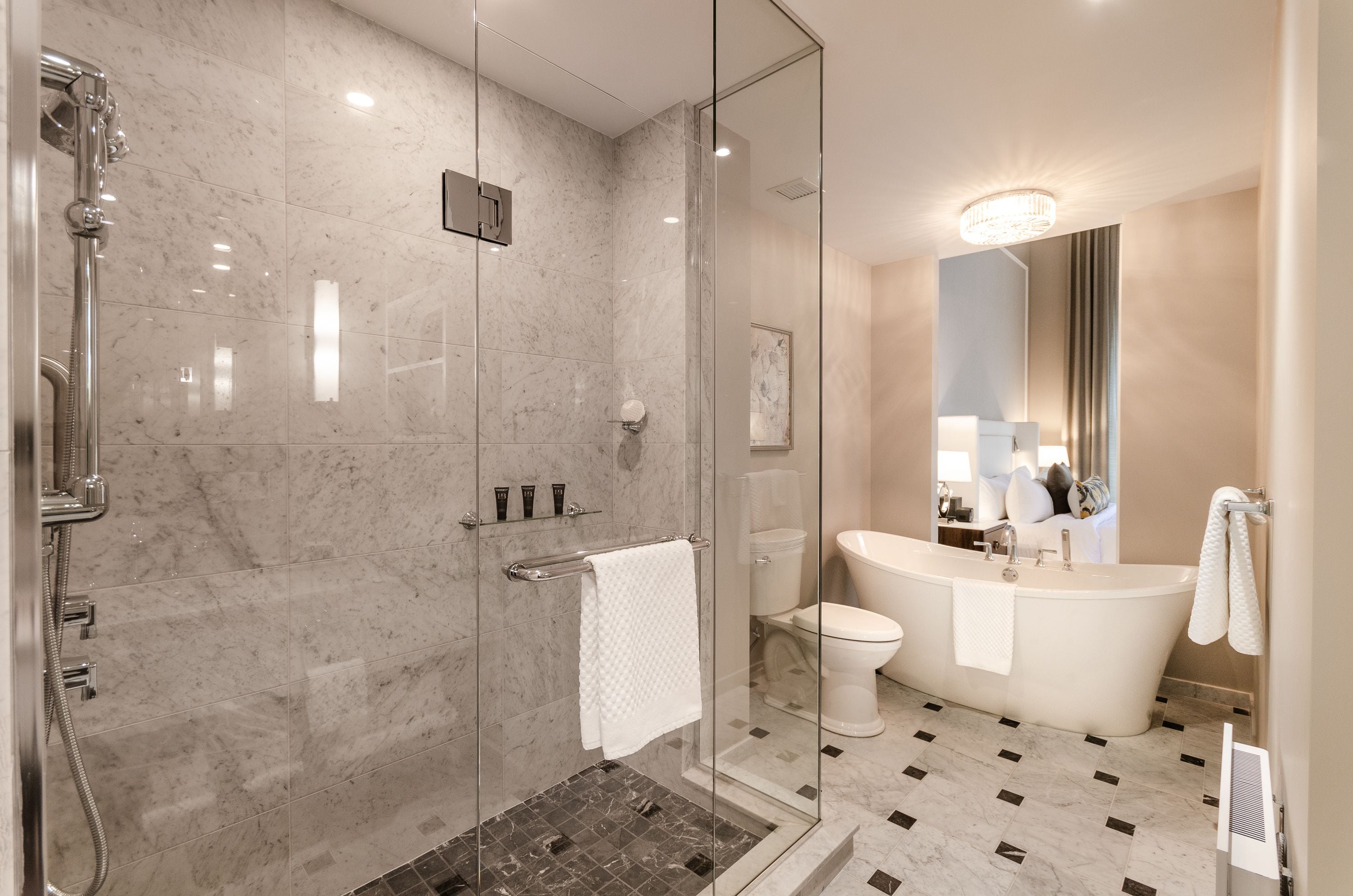 Un baño moderno con ducha envuelta en vidrio, una bañera independiente y un espejo grande sobre el lavabo.