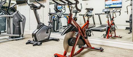 Un gimnasio con bicicletas estáticas, cintas de correr y equipo de ejercicio.