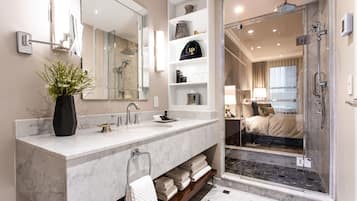 Une salle de bain moderne dotée d’un grand miroir, de deux vasques, d’une douche à parois de verre et d’une étagère intégrée pour les articles de toilette.