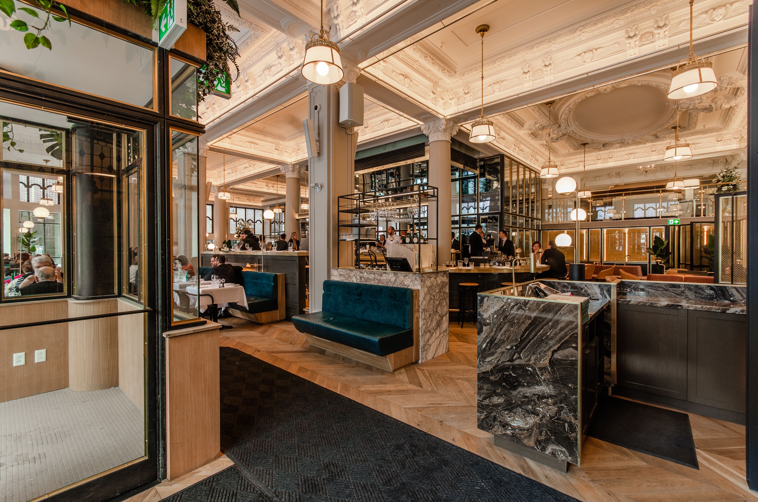 Een ruime lobby met een marmeren receptiebalie, zithoeken en een bar.