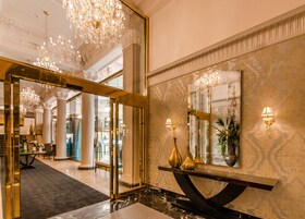 Un lobby espacioso con piso de mármol, un espejo grande y un candelabro.