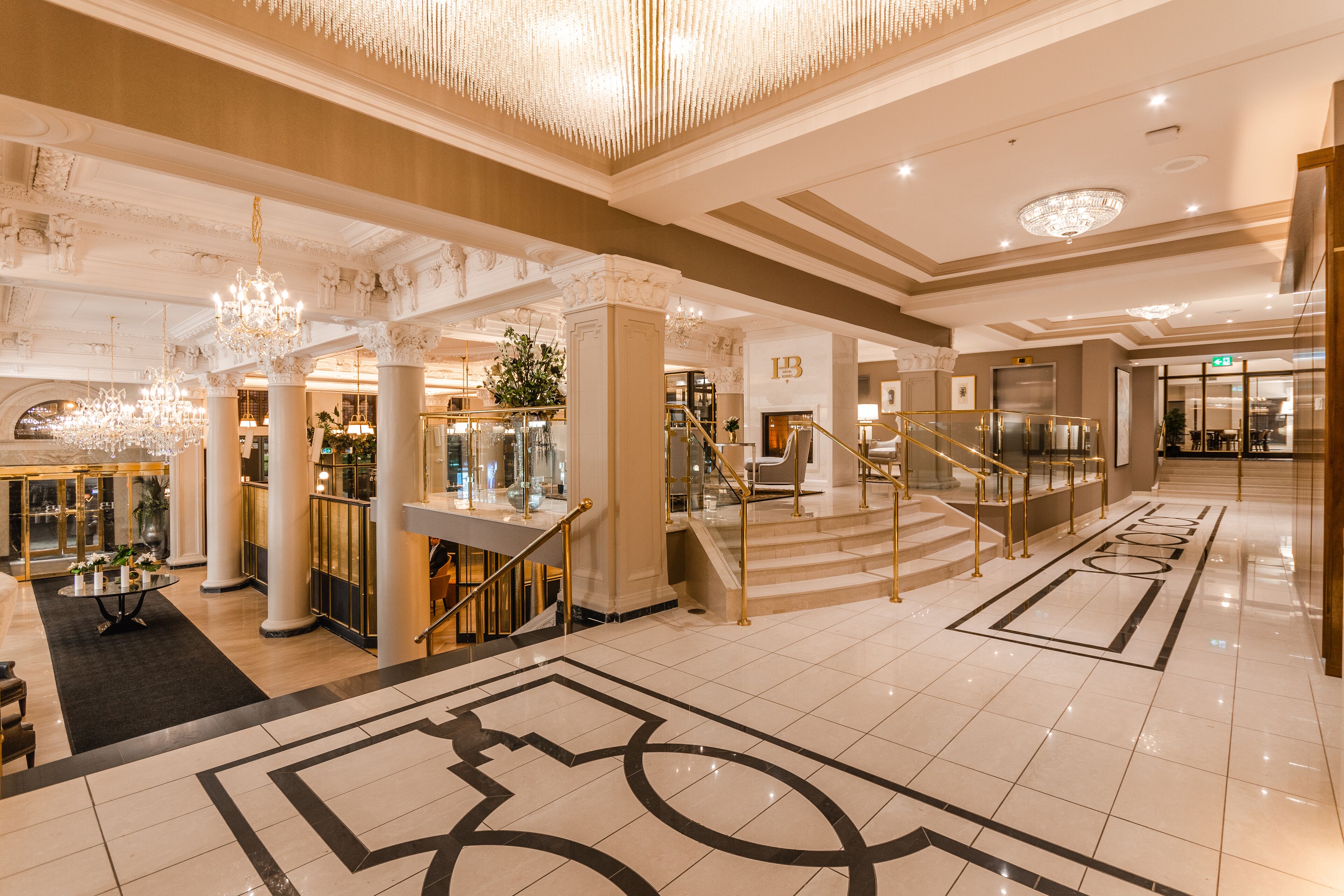 Eine geräumige Lobby mit einem prunkvollen Kronleuchter, Marmorböden und einer zentralen Treppe.