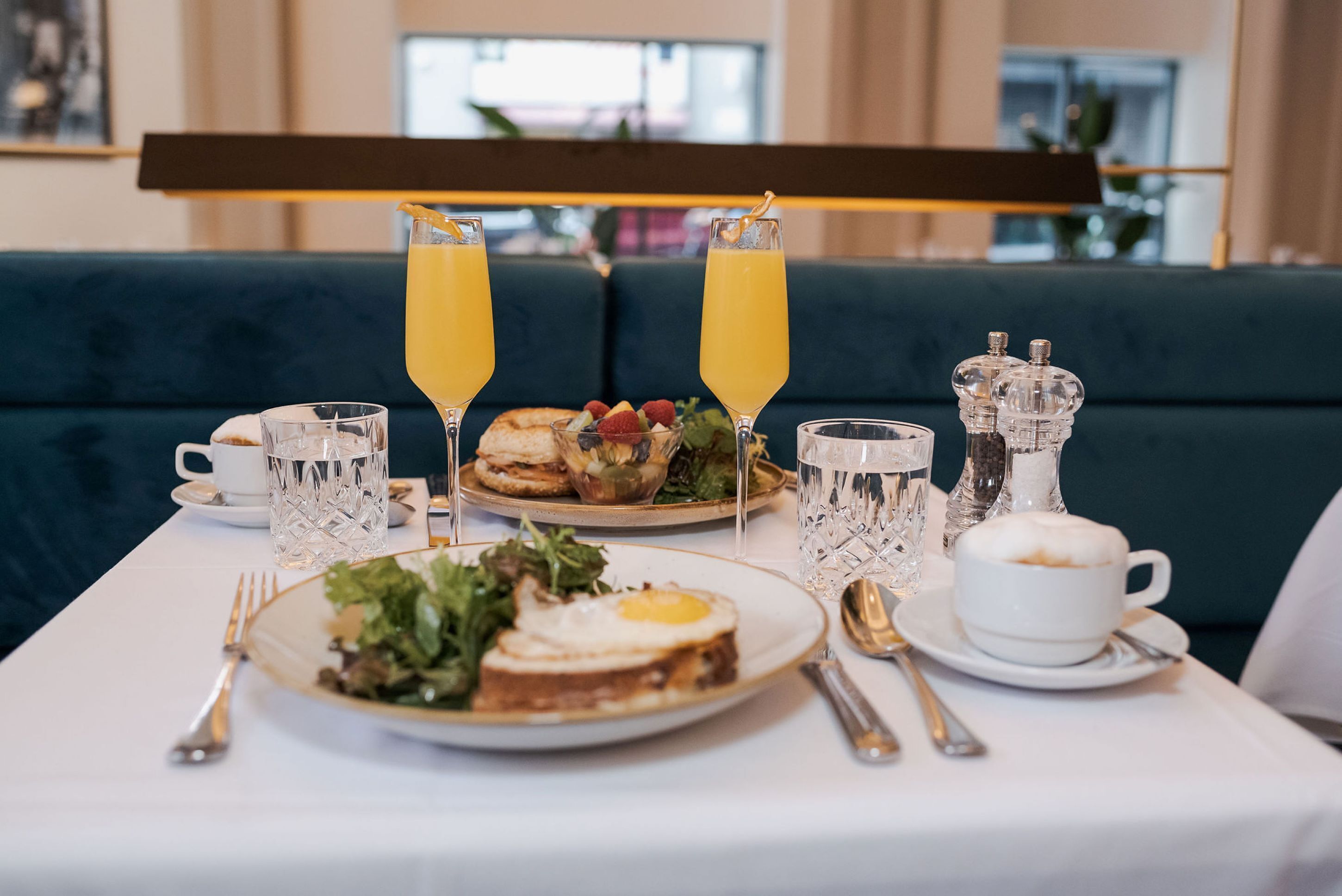 A breakfast setting with a table set for two, including plates of food, glasses of orange juice, and a cup of coffee.