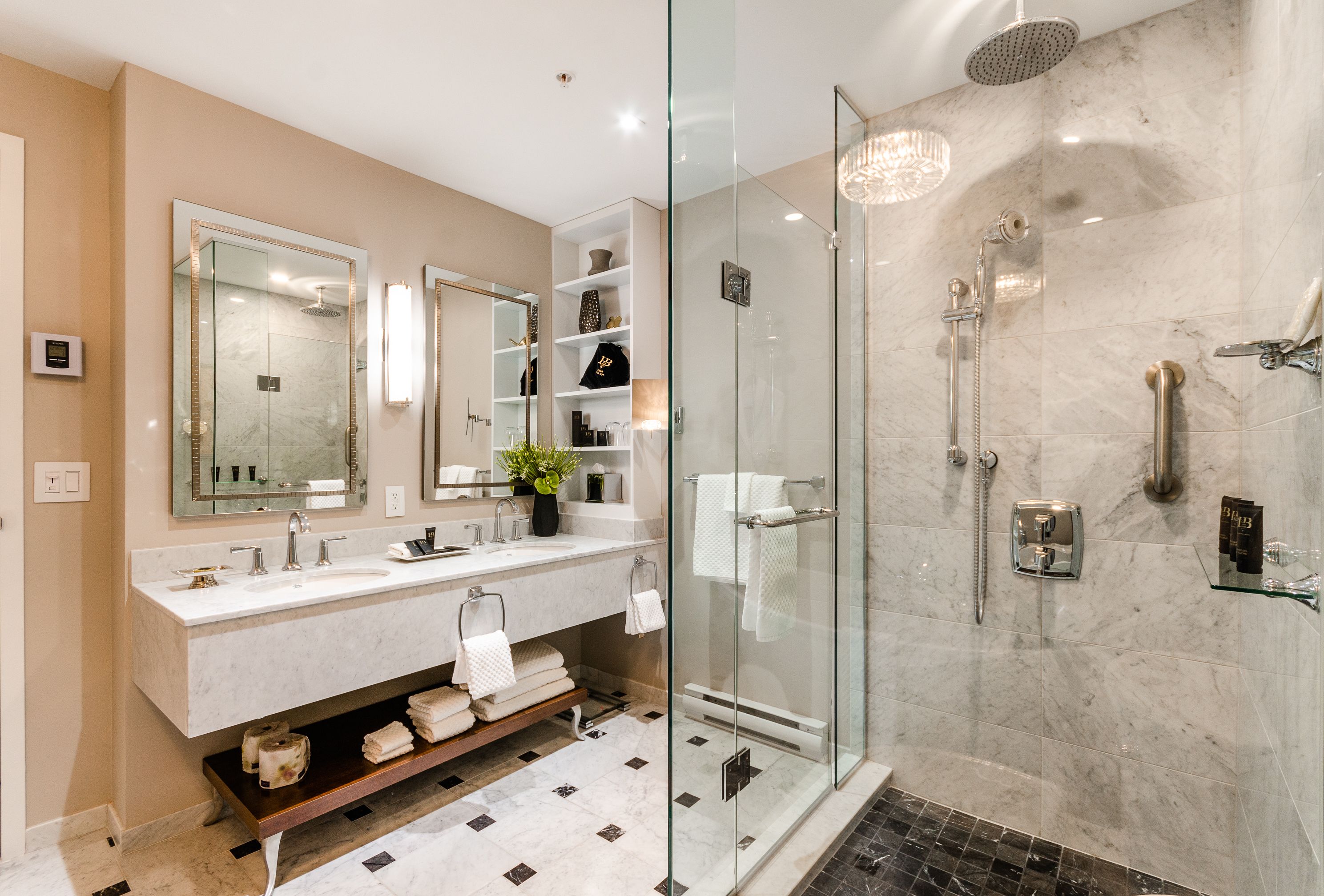 Un baño moderno con cabina de ducha de vidrio, tocador de mármol y un espejo grande.
