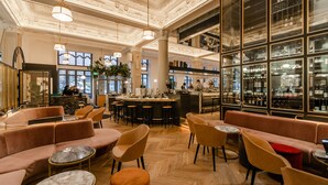 A spacious lobby with a bar area, seating arrangements, and a decorative ceiling.