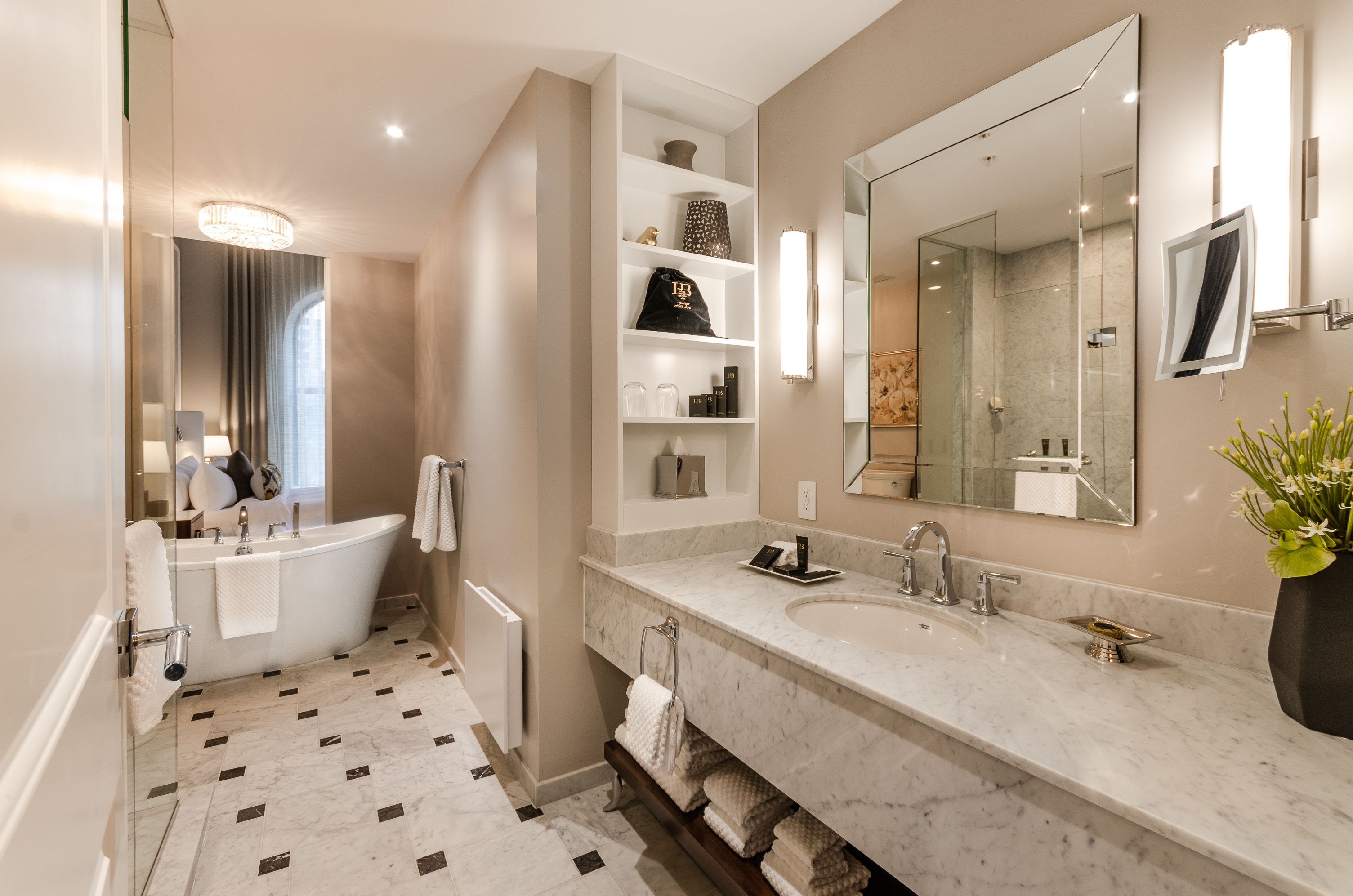 A modern bathroom with a freestanding bathtub, a large mirror, and a marble countertop.