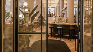 An interior with a curved doorway, a bar area, and a seating section with stools.