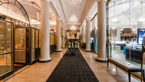 A grand lobby with a marble floor, large columns, and ornate chandeliers.