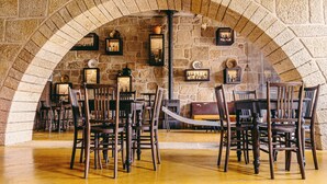 Une pièce voûtée en pierre, avec des chaises et des tables en bois, des murs de pierre et des tableaux encadrés.