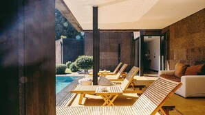 Un espace de détente extérieur moderne, doté de chaises longues en bois et d’une piscine.
