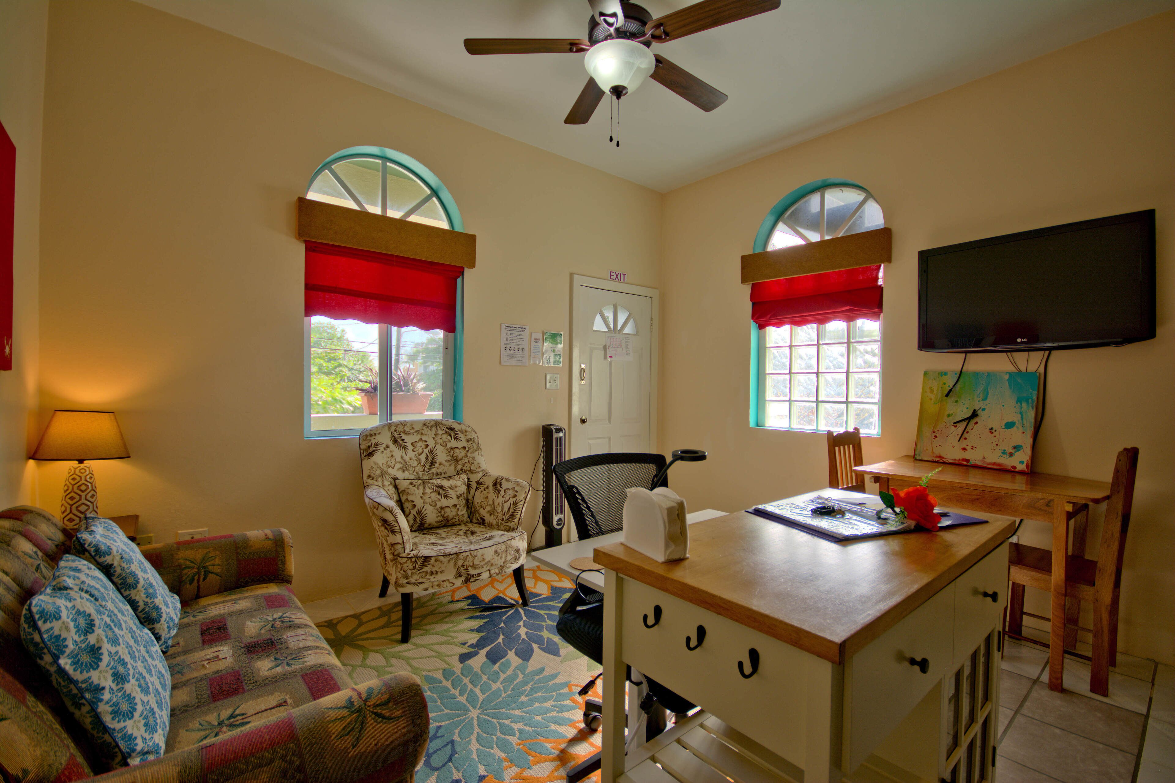 A living room with a sofa, a chair, a table, a television, and a ceiling fan.
