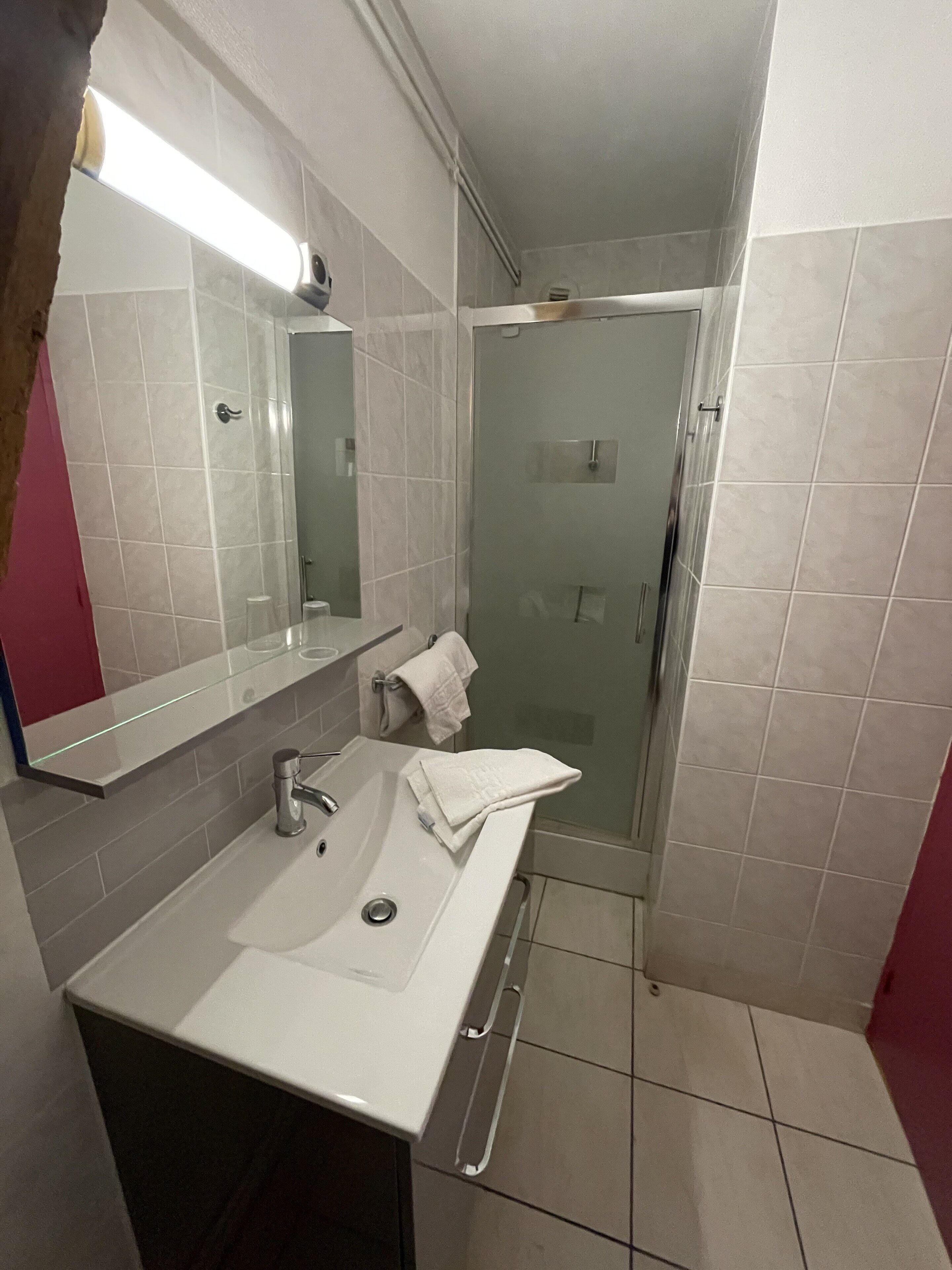 Un bagno con lavandino bianco, uno specchio e box doccia in vetro.