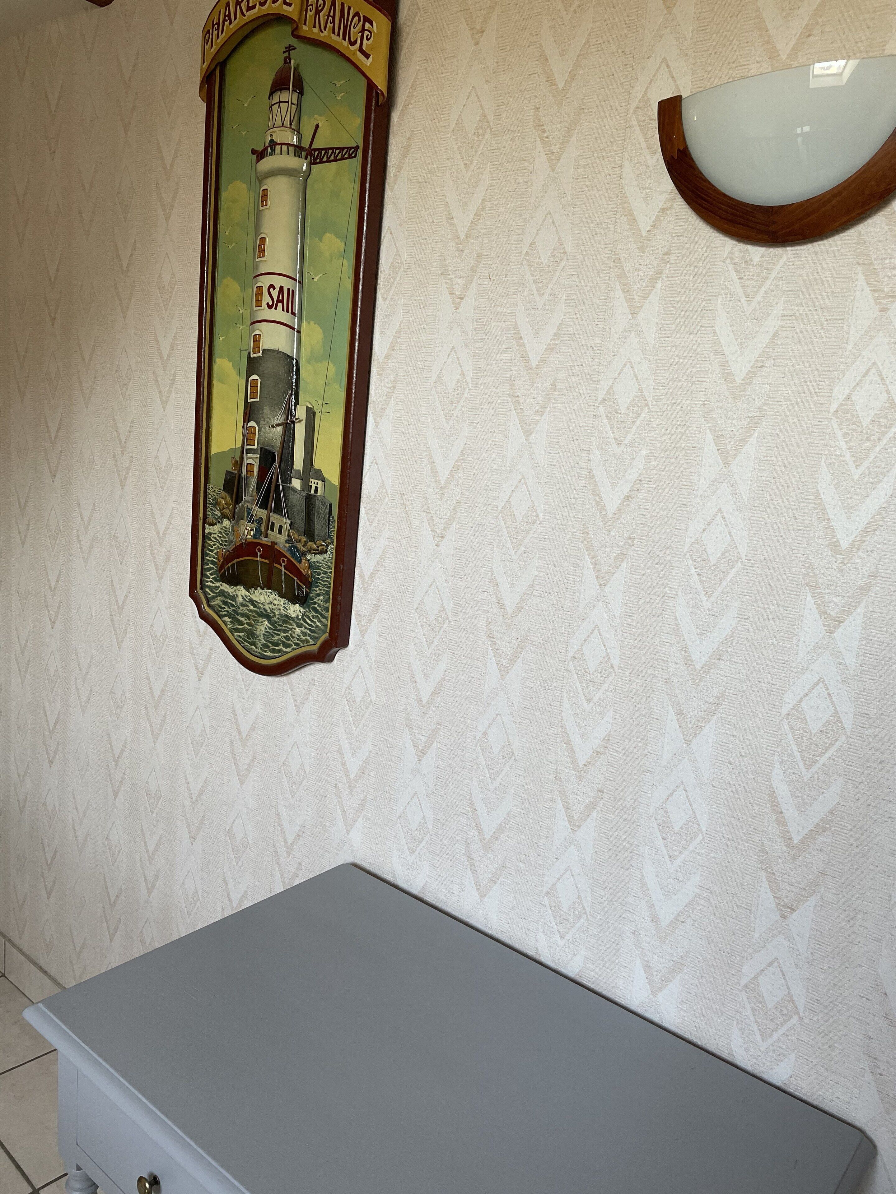 A wall with a lighthouse mural and a small table.