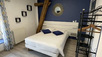 Une chambre à coucher avec un lit, un radiateur, une échelle en bois, un miroir et un luminaire au plafond.